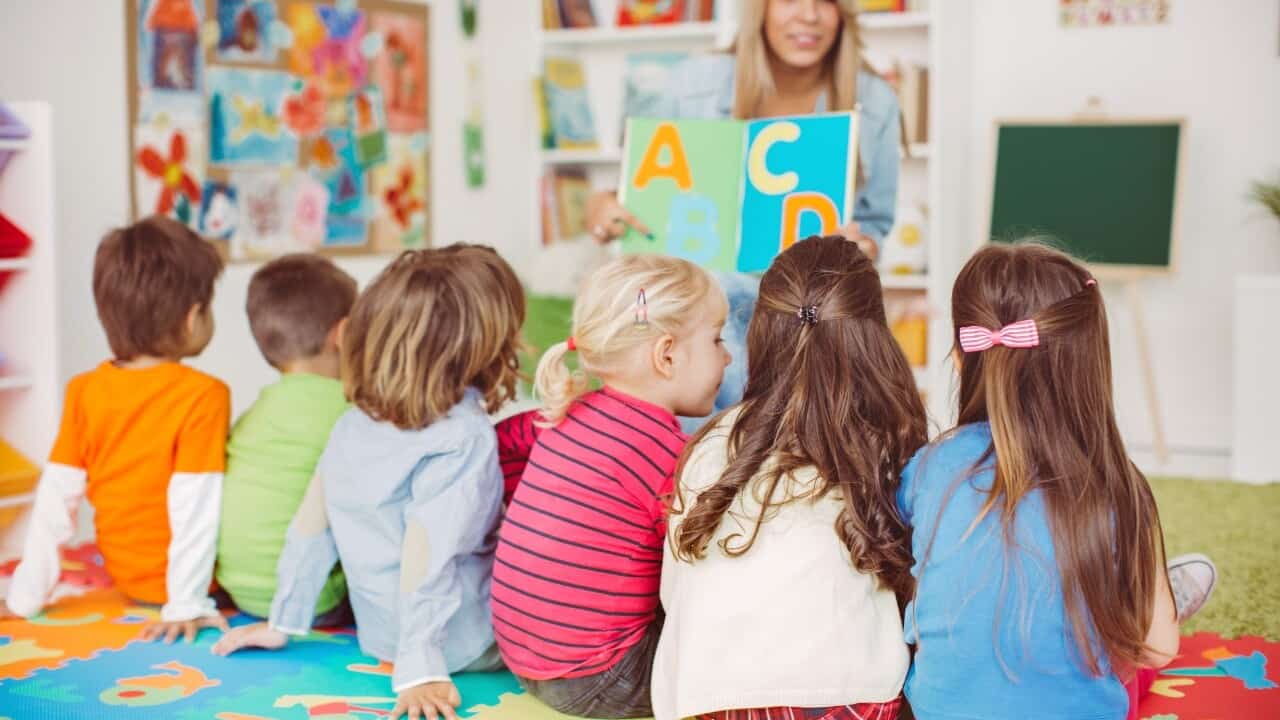 Teacher showing a book of letters to students.