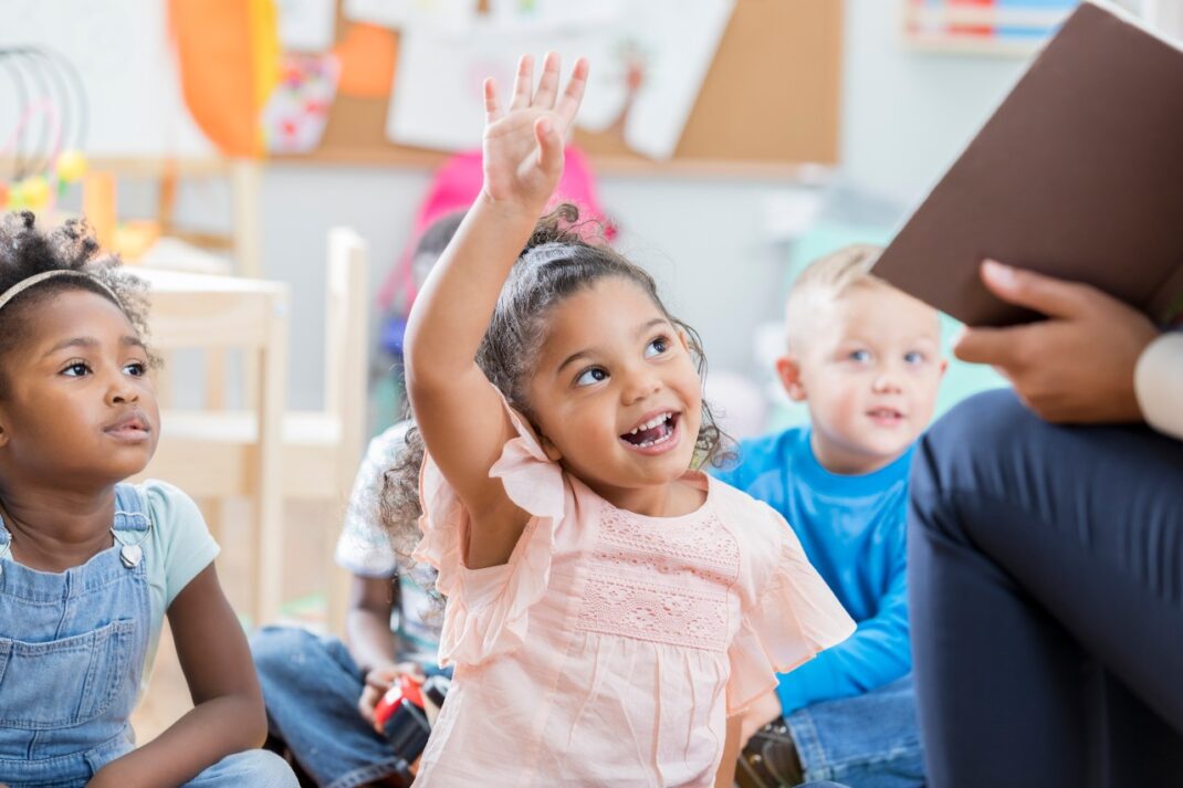 Little girl raining her hand to answer a question.